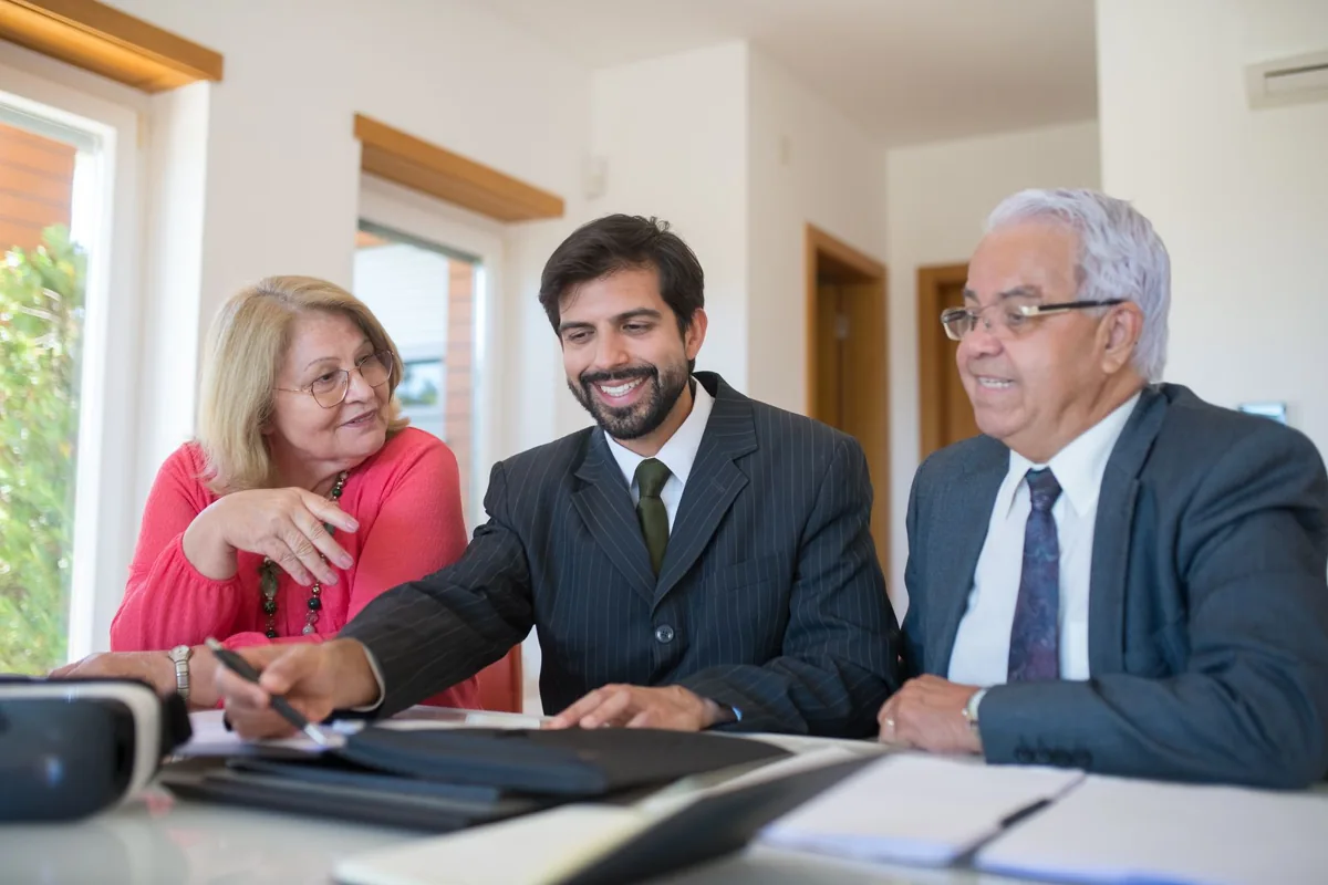 Un agente inmobiliario conversa con una pareja en una oficina. Fotografía de archivo.